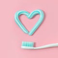 Toothbrushes and turquoise color toothpaste in shape of heart on pink background. Royalty Free Stock Photo