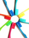 Toothbrushes of various vivid colors arranged in a star shape on a white background.