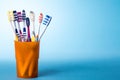Toothbrushes in yellow cup on bright blue background Royalty Free Stock Photo