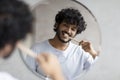 Toothcare routine concept. Young indian guy cleaning teeth in the morning using toothbrush and toothpaste Royalty Free Stock Photo