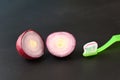 Toothpaste applied to the toothbrush and red onion cut in half on a dark background Royalty Free Stock Photo