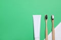 Toothpaste, brushes and towel on green background, flat lay. Space for text