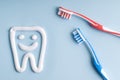 Toothpaste in a form of a tooth and toothbrushes on blue