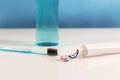 Toothpaste laid on a white background extruded tricolor part of the toothpaste, in the left part placed a blue toothbrush, in the