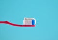Toothpaste on a pink toothbrush close-up on a blue light background. Royalty Free Stock Photo