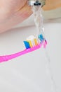 Toothpaste on toothbrush in hand, in the bathroom sink. Royalty Free Stock Photo