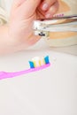 Toothpaste on toothbrush in hand, in the bathroom sink. Royalty Free Stock Photo