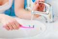 Toothpaste on toothbrush in hand, in the bathroom sink. Royalty Free Stock Photo