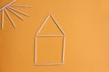 Toothpicks in the form of a house and the sun on an orange background Royalty Free Stock Photo