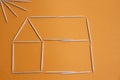 Toothpicks in the form of a house and the sun on an orange background Royalty Free Stock Photo