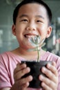 Toothy smiling face of asian children holding succulent pot in hand