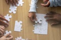 Top above close up view multiracial human hands assembling puzzle