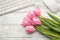 Top above close up view photo of bouquet of tender pastel tulips computer keyboard and mouse on white wooden desk