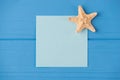 Top above overhead view close-up photo of a blank note with a small starfish isolated on blue wooden background with copyspace Royalty Free Stock Photo