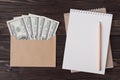 Top above overhead view flat lay photo of craft envelope full of dollars blank notebook pencil isolated on wooden background with Royalty Free Stock Photo