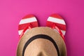 Top above overhead view photo of a pair of flipflops and a hat isolated on pink background