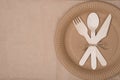 Top above overhead view photo of a set of wooden cutlery lying on a paper plate placed to the right side isolated on craft paper