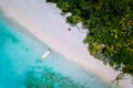 Top down aerial view of exotic tropical sandy beach with blue lagoon, palm trees and linely boat moored Royalty Free Stock Photo