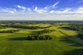 Top aerial view of green fields and meadows in summer. Abstract landscape with lines of fields, grass, trees, sunny sky and lush