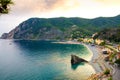 Top aerial view of green hills, rocks, harbor and beach of Monterosso town village at sunset dusk, Genoa Gulf, Ligurian Sea, Natio