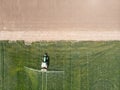 Top aerial view of the tractor spraying the chemicals on the green field of grain. Agriculture concept with tractor in the grain Royalty Free Stock Photo