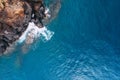Top aerial view of turquoise Atlantic ocean water waves crashing on rocks on the Portuguese Madera island seashore