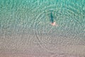 Top, aerial view. Young beautiful woman in a hat and white bikini swimming in sea water on the sand beach. Drone, copter photo. Royalty Free Stock Photo