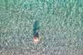 Top, aerial view. Young beautiful woman in a hat and white bikini swimming in sea water on the sand beach. Drone, copter photo. Royalty Free Stock Photo