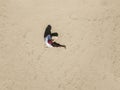 Top aerial view of young hipster sitting on the abstract sandy sea beach. summer exotic concept d Royalty Free Stock Photo