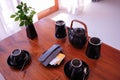 Tea / coffee set in black porcelain on wooden coffee table in tropical hotel resort room Royalty Free Stock Photo