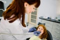 Top angle view of cute red haired girl lying on dentist chair with open mouth while young female doctor curing her teeth Royalty Free Stock Photo
