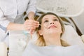 Top angle view of face of beautiful young woman getting face skin treatment in modern beauty center. Cosmetician is Royalty Free Stock Photo