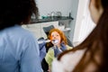 Top angle view of little girl patient having dental treatment at dentist`s office. Team of two multiethnic female