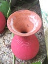 A top angle view of a vibrant red colored earthen pot in a garden