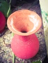 Top angle view of a vibrant red colored earthen pot placed in a garden