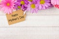 Top border of flowers with Mothers Day gift tag against white wood