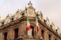 The top of building Edificio La Esmeralda with mexican flags, a clock, and many details and ornaments, Mexico City