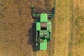 Top central view of an agricultural machine - green combine - working at a fertile land full of ready rapeseed plants