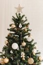 The top of a Christmas artificial tree standing at home. Beige golden shiny star at the top of the tree. Decorating a Christmas