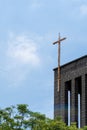 top of a church with a rusty metal cross, the church is made of stone with clear blue sky. mexico