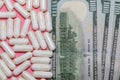 Top close up shot of white pills and a few hundreed dollar bills next to them on pink background. Healthcare, medical, Royalty Free Stock Photo