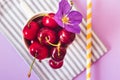 Top view of cherries on a stripped cloth and a yellow stripped straw on purple background Royalty Free Stock Photo