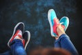 Top close up view of young couple legs in sneakers sitting on pier near to the sea full of jellyfish