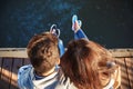 Top close up view of young couple sitting on pier near to the sea full of jellyfish.