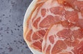 Top close view of a plate of dry coppa on a gray mottled tabletop