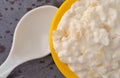 Top close view of a small yellow bowl of pineapple cottage cheese with a spoon to the side on a gray table