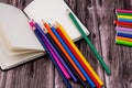 Top closeup of an open notebook with a pack of colored markers and pencils on the wooden background Royalty Free Stock Photo