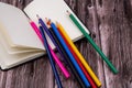 Top closeup of an open notebook with a pack of colored pencils on the wooden background Royalty Free Stock Photo