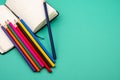 Top closeup of a pack of colored pencils on an open notebook on the green background Royalty Free Stock Photo