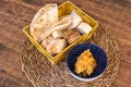 Top closeup of pita bread in a yellow basket and fried chicken in a blue bowl on a woven placemat